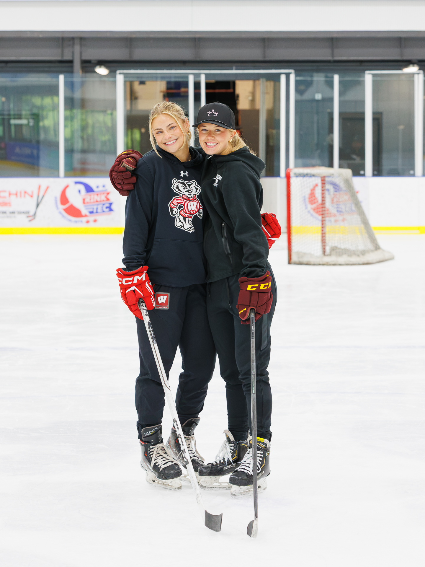 Two hockey coaches smiling together on the ice