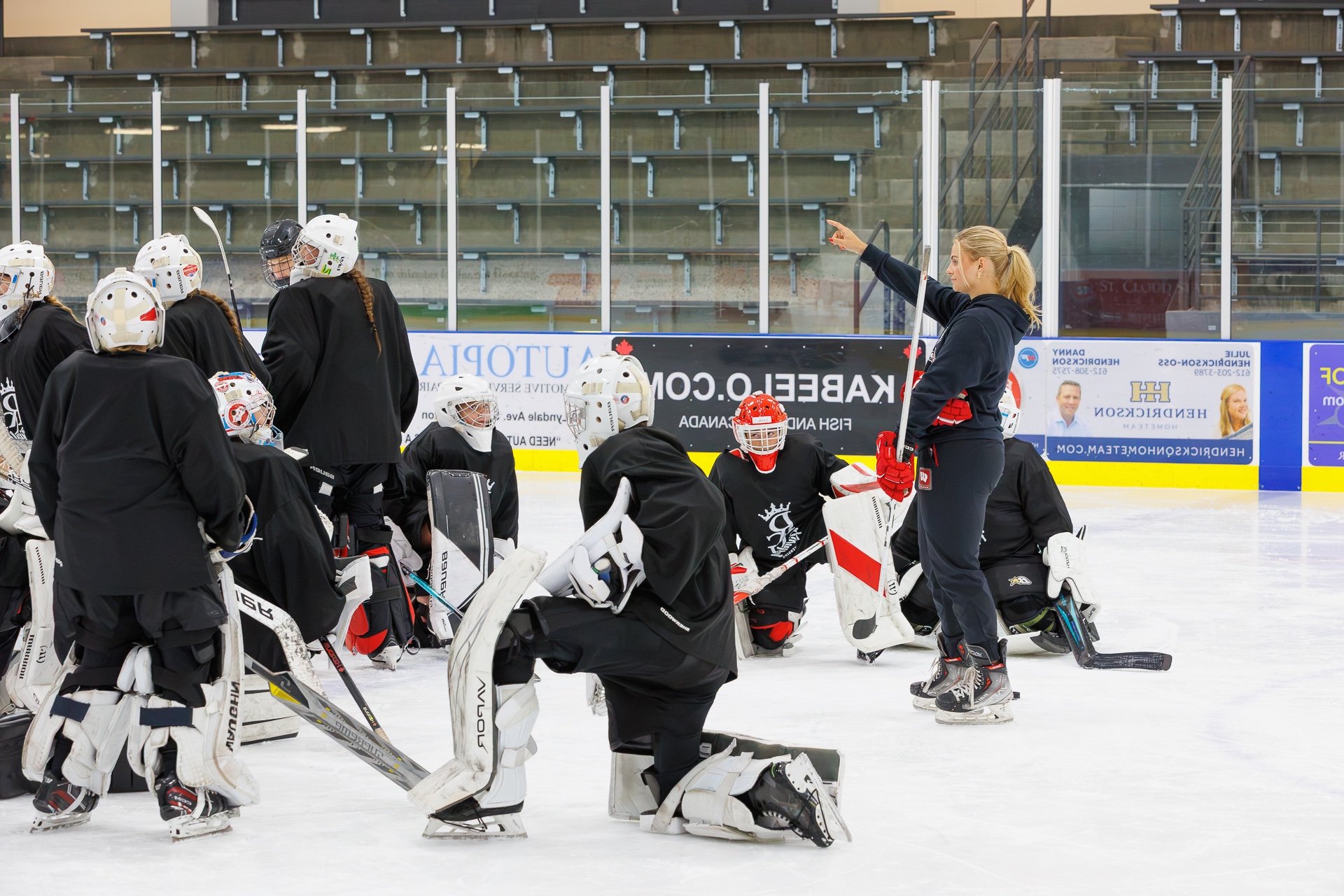 Coach instructing a group of goaltenders on the ice